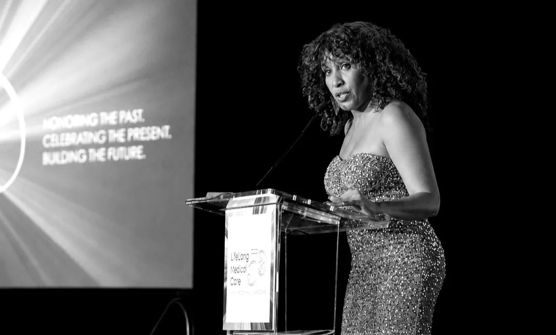 Nikki Thomas speaking at a gala in black and white